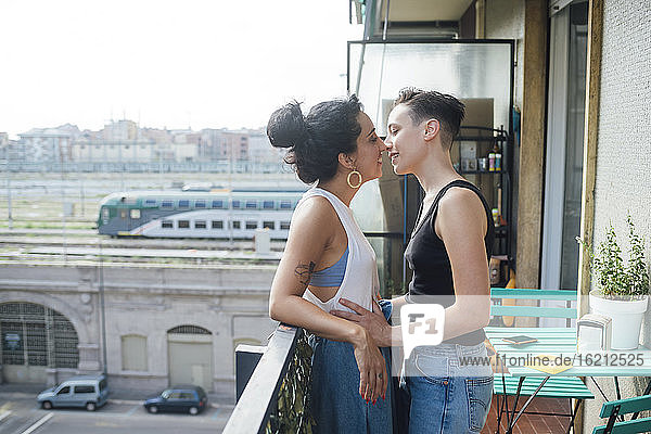 Lächelnde lesbische Frauen  die sich auf dem Balkon küssen