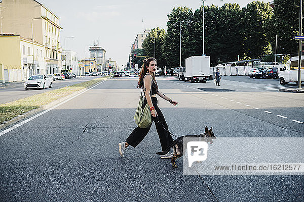 Frau überquert Straße mit Hund in der Stadt