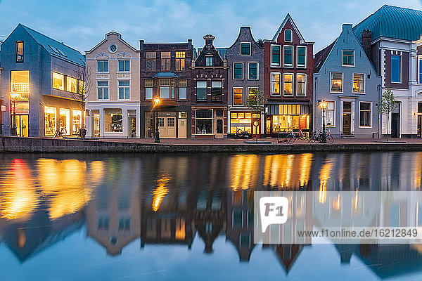Niederlande  Südholland  Leiden  Reihe historischer Stadthäuser  die sich in der Abenddämmerung im Rheinkanal spiegeln