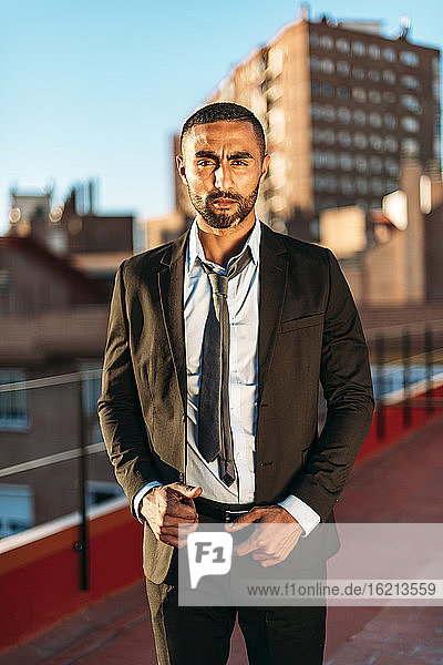 Well-dressed young male entrepreneur standing on rooftop in city