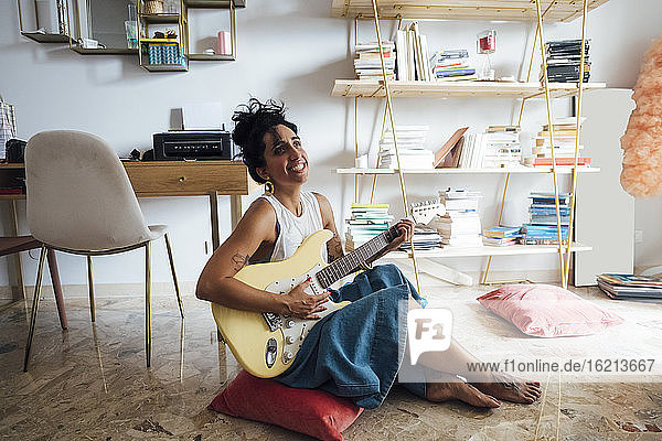 Frau spielt Gitarre im Wohnzimmer