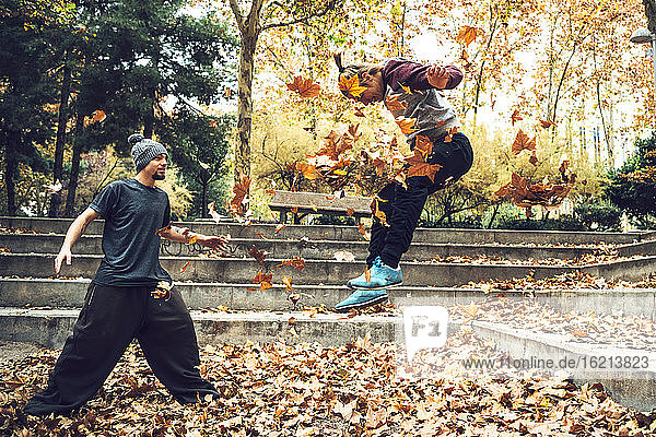 Junger Mann sieht seinen Freund an  der im Herbst im Park springt