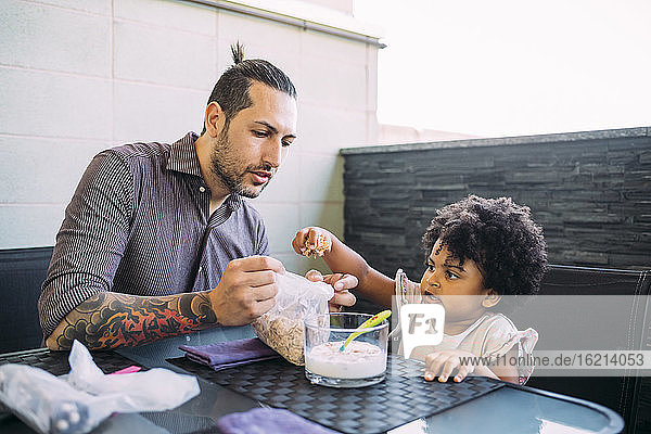 Father and daughter with food and milk on dining table at home