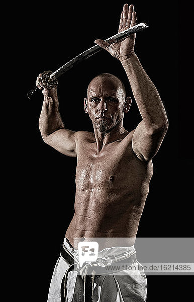Deutschland  Bayern  Älterer Mann macht Karate mit Schwert  Porträt