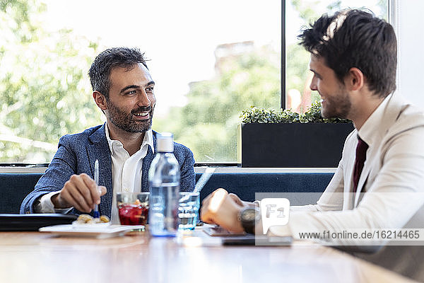 Lächelnde Geschäftsleute diskutieren bei einem Treffen im Restaurant
