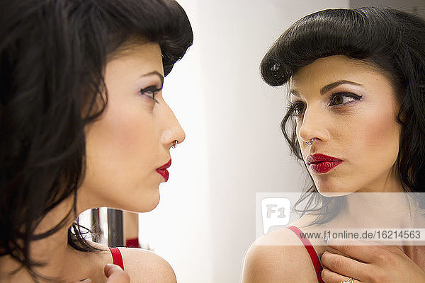 Junge Frau mit Nasenpiercing schaut in den Spiegel