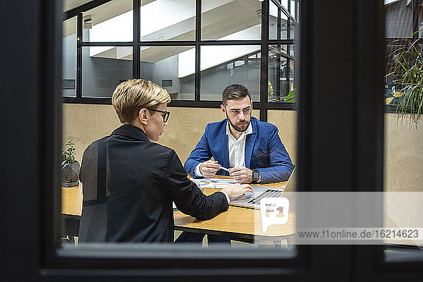Geschäftskollegen planen eine Strategie  während sie in einem Sitzungssaal über einen Laptop diskutieren