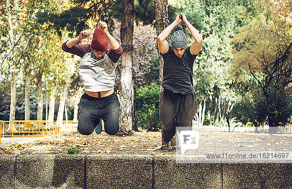 Männliche Freunde springen im Herbst in einem öffentlichen Park