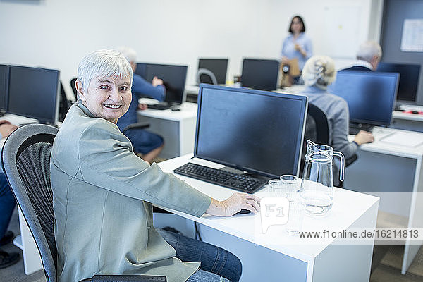 Confident senior woman attending computer course