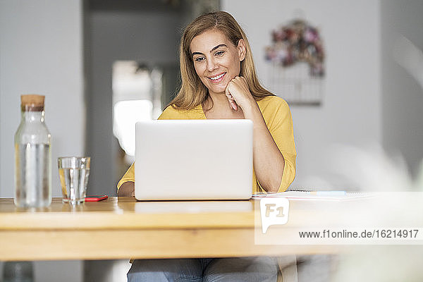Lächelnde reife Frau benutzt Laptop zu Hause
