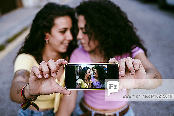 Nahaufnahme eines lesbischen Paares  das ein Selfie mit einem Smartphone in der Stadt macht