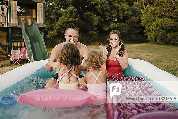 Glückliche Familie in einem aufblasbaren Schwimmbad im Garten