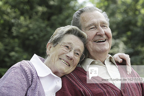 Deutschland  Köln  Älteres Paar sitzt im Park  lächelnd