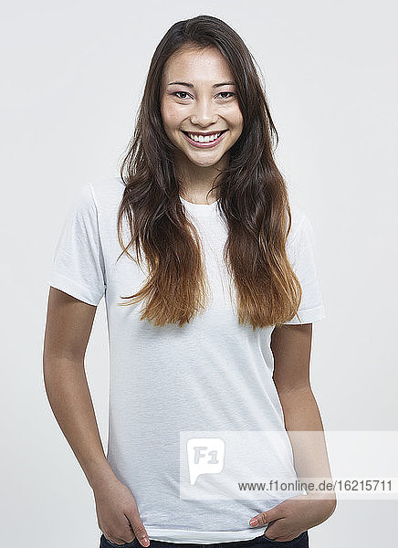 Portrait of young woman against white background  smiling