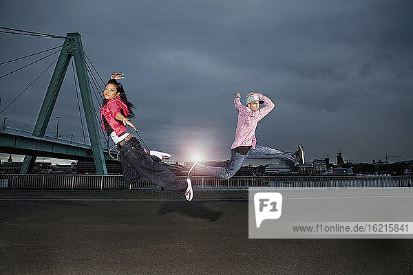 Deutschland  Köln  Mann und Frau springen  Skyline im Hintergrund