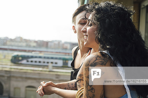 Frau küsst Partner auf dem Balkon
