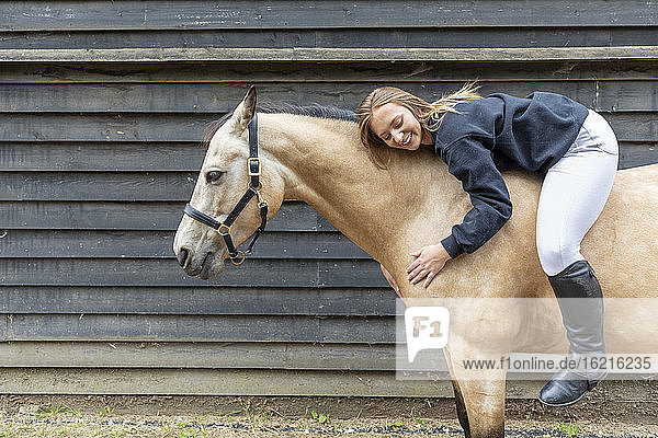 Junge Frau auf dem Rücken ihres Pferdes liegend
