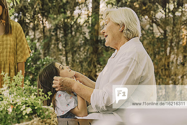 Happy senior woman playing with cute granddaughter in yard