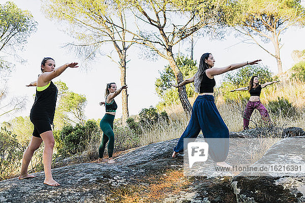 Yoga instructor exercising with women in forest