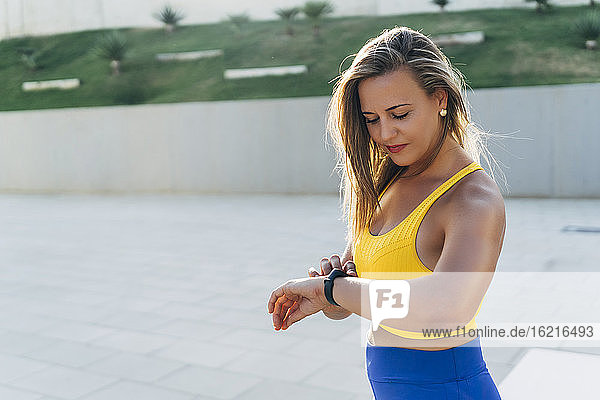 Junge blonde Frau überprüft Smartwatch