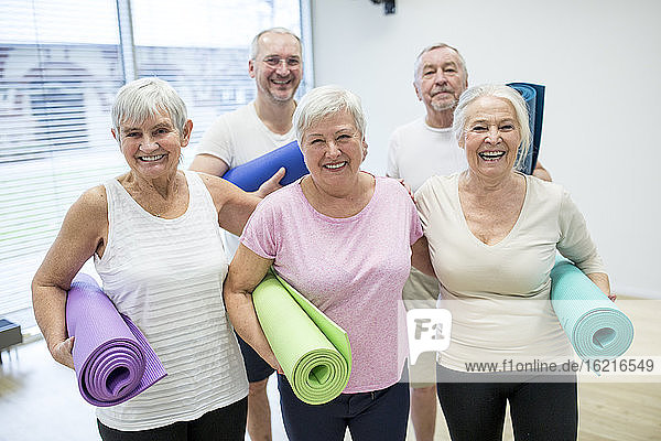 Gruppe glücklicher Senioren mit Matten für den Yoga-Kurs