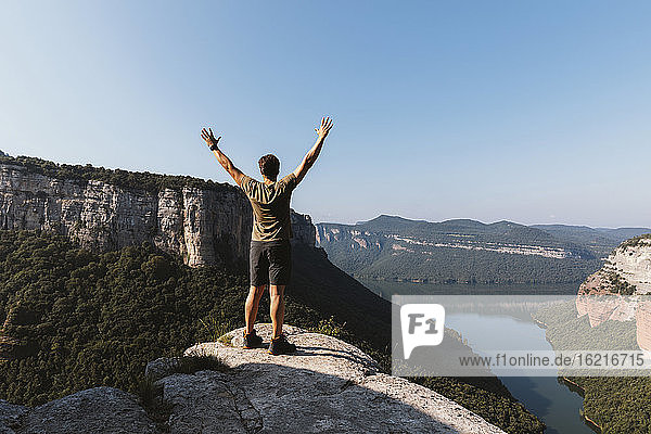 Mann mit erhobenen Armen auf einem Berg vor klarem Himmel in Vilanova de Sau  Katalonien  Spanien