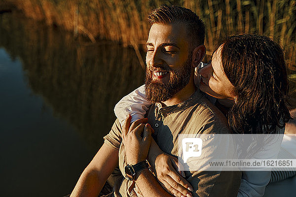Glückliches  zärtliches Paar  das sich bei Sonnenuntergang an einem See umarmt
