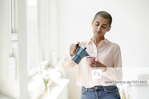 Woman pouring coffee into cup in a loft