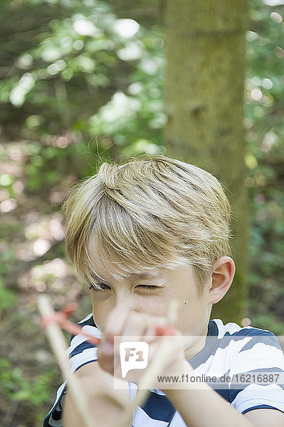 Germany  Bavaria  Munich  Boy aiming with slingshot  close up