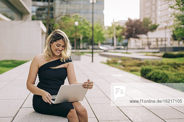 Fröhliche Geschäftsfrau mit Laptop im Freien