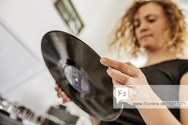 Nahaufnahme einer Frau im mittleren Erwachsenenalter  die zu Hause eine Schallplatte hält