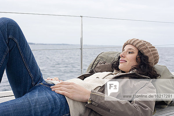 Germany  Baltic Sea  Lübecker Bucht  Young woman lying on deck of yacht  portrait