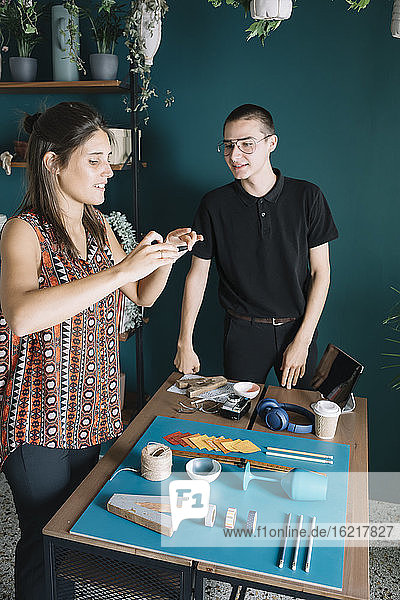 Junges kreatives Paar  das ein Smartphone-Foto von einer Dekoration auf dem Tisch macht