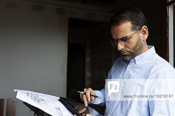 Architect at work with tablet and construction plan