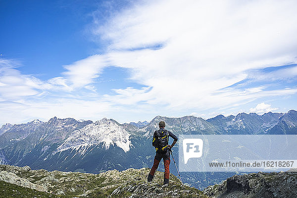 Wanderer steht auf dem Gipfel und schaut auf die Berge  Westliche Rätische Alpen  Sondrio  Italien
