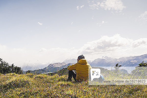 Mann betrachtet die Aussicht  während er auf einem Berg in Patagonien  Argentinien  Südamerika sitzt