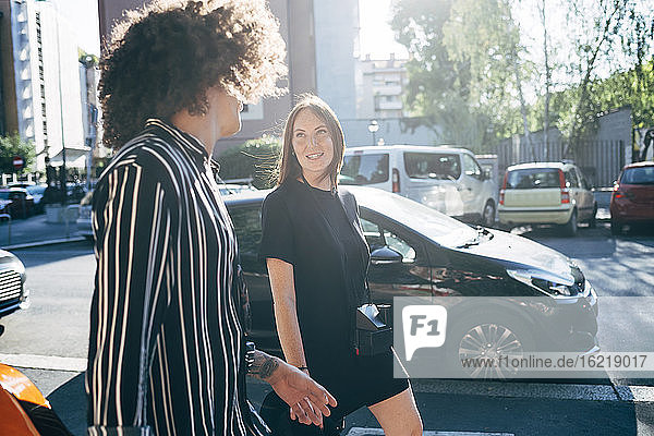 Paar im Gespräch beim Spaziergang auf der Straße in der Stadt an einem sonnigen Tag
