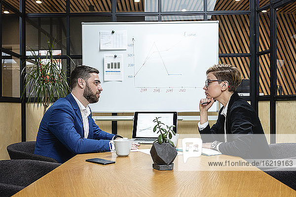 Selbstbewusste Geschäftsfrau hört zu  während sie eine Führungskraft bei einem Vorstellungsgespräch im Sitzungssaal ansieht
