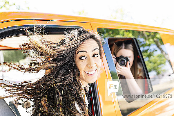 Frau fotografiert andere Frau  die in einem Van sitzt