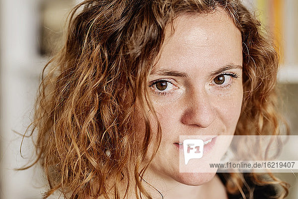 Close-up portrait of mid adult woman with wavy hair at home