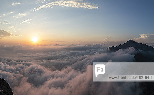 Idyllische Aufnahme eines von Wolken bedeckten Berges bei Sonnenaufgang in den Bergamasker Alpen  Italien
