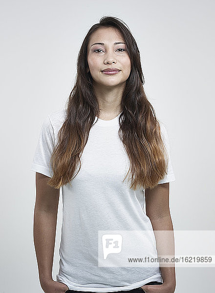Portrait of young woman against white background  smiling