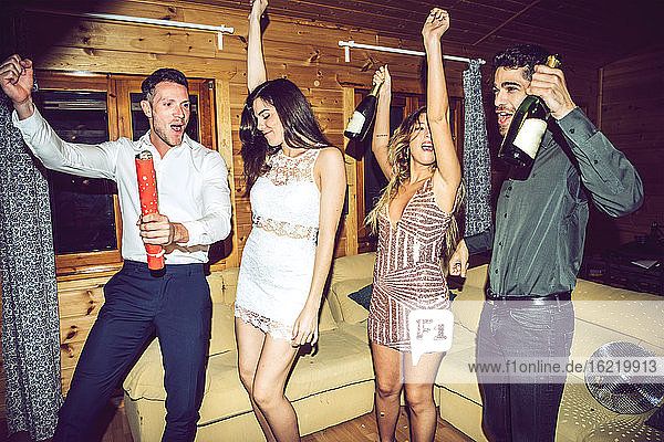 Fröhliche Freunde mit Champagnerflaschen tanzen und haben Spaß in der Partei