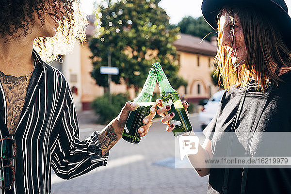 Glückliches Paar stößt auf Bierflaschen an  während sie in der Stadt stehen