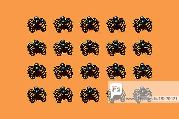 Pattern of black plastic spiders against orange background
