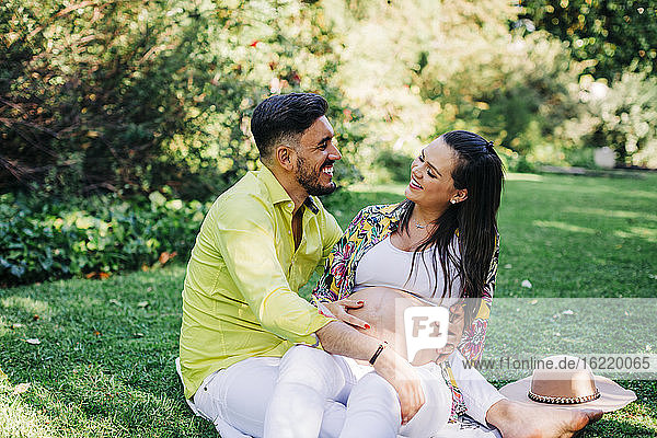 Fröhlicher Mann und schwangere Frau verbringen ihre Freizeit zusammen im Park