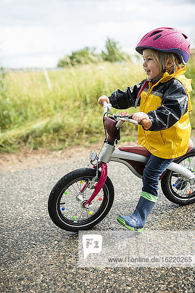 Kleinkind-Mädchen mit rosa Fahrradhelm auf Balance-Fahrrad
