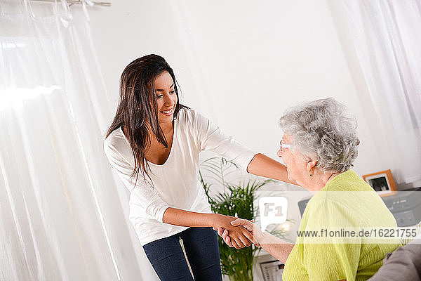cheerful young girl taking care of an elderly senior woman at home