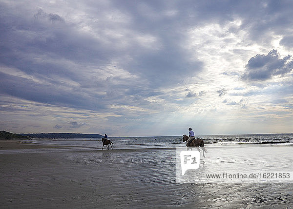 Normandy (France)  two horseriders at full gallop on a beach