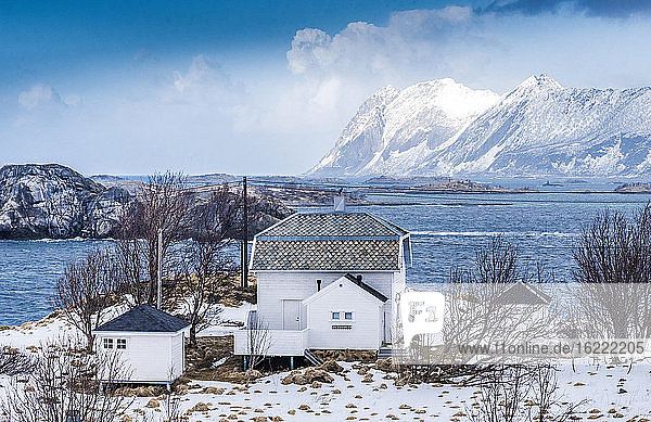 Norwegen  Bezirk Tromso  Insel Senja  Haus im Schnee am Rande des Fjordes